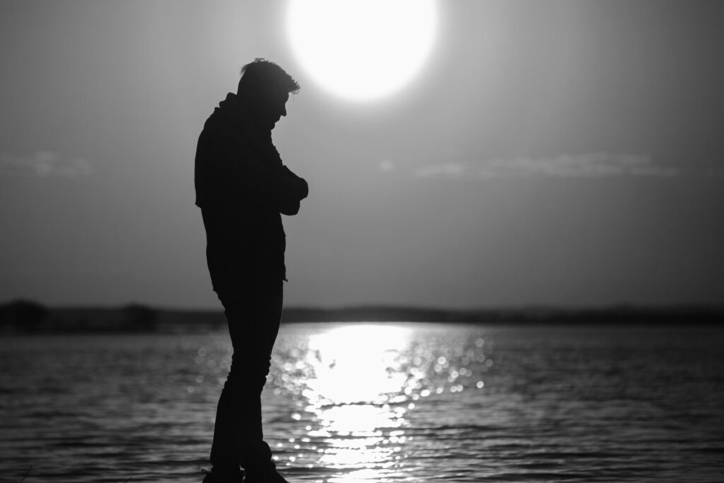 Person standing alone at sunrise feeling disconnected and reflecting on life direction